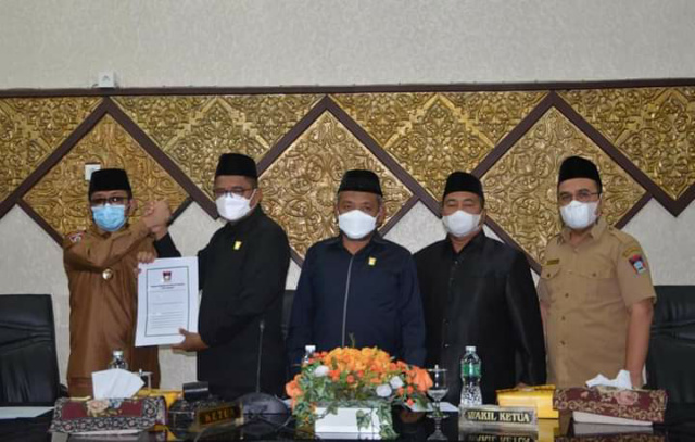 SAHKAN - Ketua DPRD Syafrial Kani serahkan Perda Retribusi Jasa Umum usai disahkan dalam paripurna DPRD kepada Walikota Padang Hendri Septa.